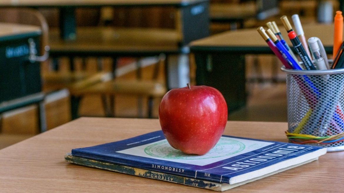 Яблуко на книжках і олівці на вчительському столі