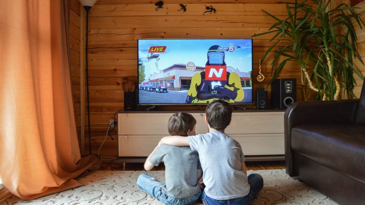 Двоє хлопчиків дивляться мультфільм по телевізору вдома
